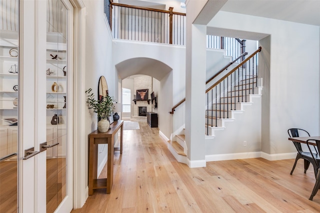 foyer entrance featuring arched walkways, a towering ceiling, a fireplace, and stairway