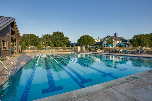 community pool with a patio and fence
