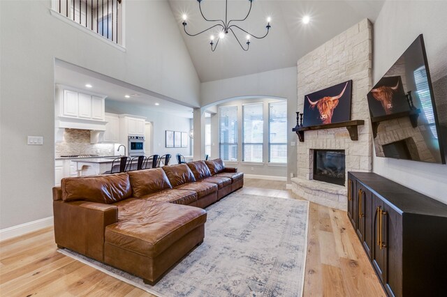 living area with baseboards, arched walkways, and light wood-type flooring