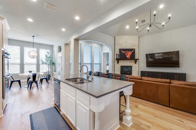 kitchen featuring a sink, open floor plan, light wood-style floors, a notable chandelier, and visible vents