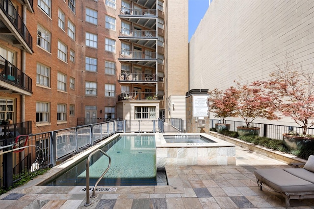 community pool featuring fence and a hot tub
