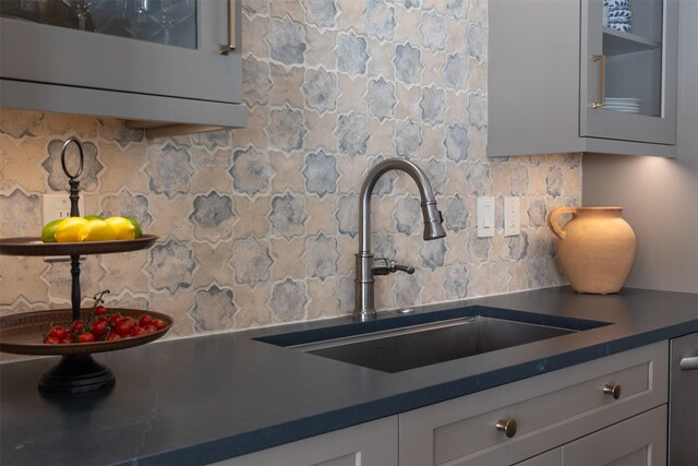 kitchen with dark countertops, tasteful backsplash, a sink, glass insert cabinets, and white cabinets