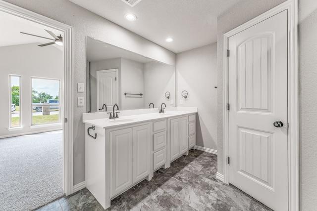 full bath with a sink, baseboards, a textured ceiling, and double vanity