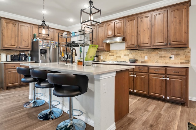 1728 Rio Secco Dr, Fort Worth, TX 76131 - kitchen featuring light wood finished floors, under cabinet range hood, brown cabinets, and appliances with stainless steel finishes