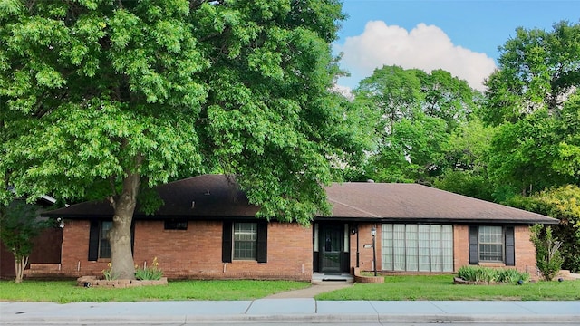 view of front facade with an attached garage, brick siding, and a front yard