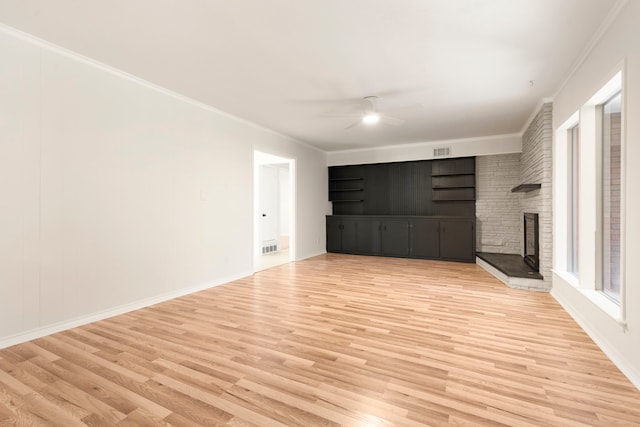 unfurnished living room featuring visible vents, ceiling fan, light wood-style flooring, crown molding, and a stone fireplace