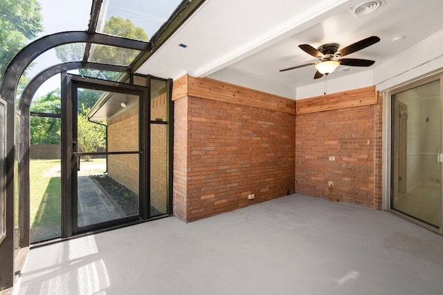 interior space with a ceiling fan, brick wall, visible vents, and concrete flooring