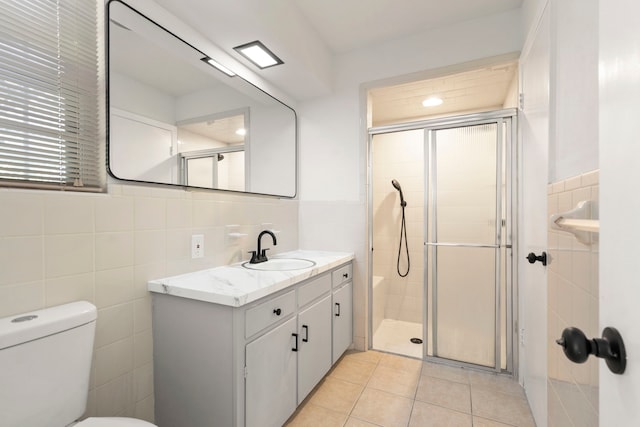 full bathroom with toilet, a stall shower, tile patterned floors, tile walls, and vanity