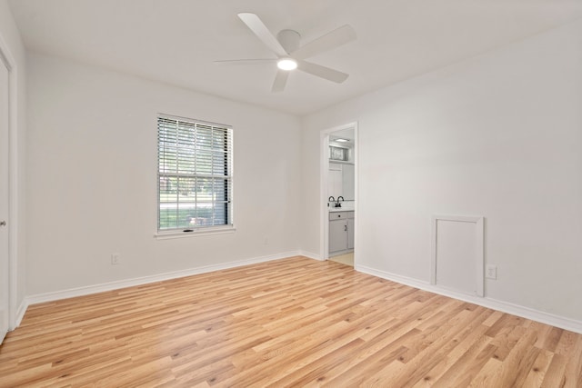 spare room with light wood-style flooring, baseboards, ceiling fan, and a sink