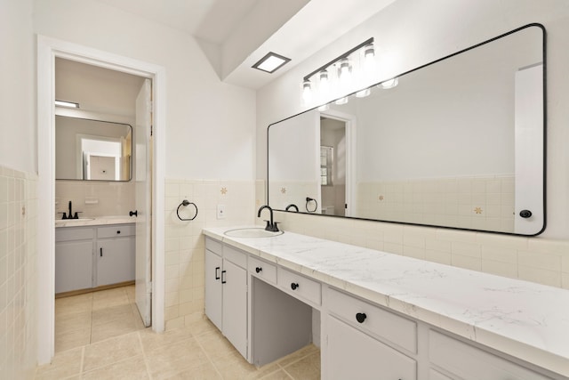 bathroom with tile walls, tile patterned flooring, vanity, and a wainscoted wall