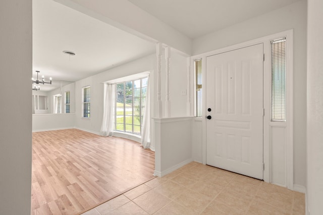 foyer entrance with light wood finished floors, a chandelier, and baseboards