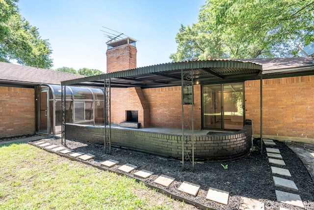 rear view of house featuring a sunroom, brick siding, a chimney, and a patio