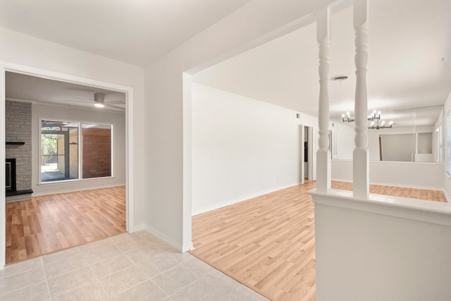 corridor featuring a chandelier, baseboards, and light wood-style floors