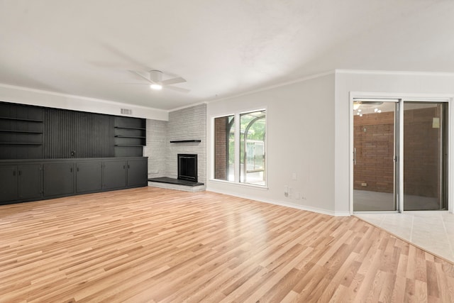 unfurnished living room with light wood-type flooring, visible vents, a fireplace, crown molding, and a ceiling fan