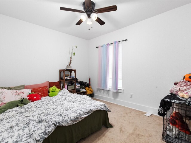 bedroom with ceiling fan, light carpet, and baseboards