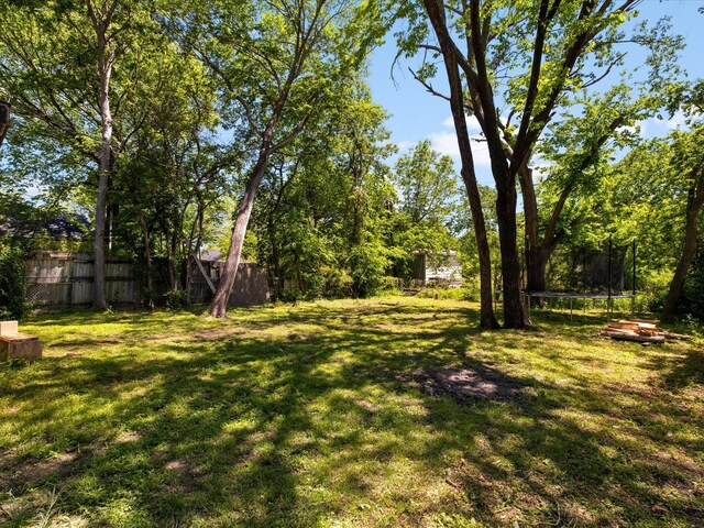 view of yard featuring a trampoline and fence