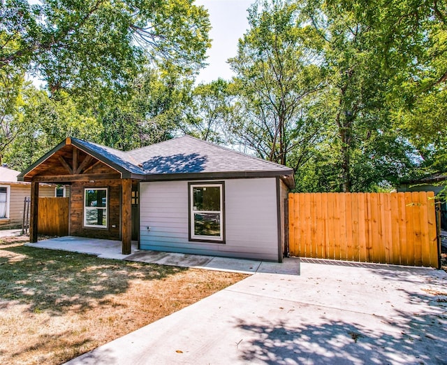 single story home with roof with shingles, fence, and a patio area