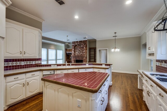 1405 Chesapeake Dr, Plano, TX 75093 - kitchen with a brick fireplace, ceiling fan, a kitchen island, tasteful backsplash, and dark wood-type flooring