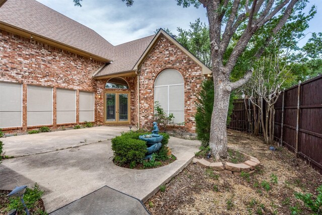 1405 Chesapeake Dr, Plano, TX 75093 - view of front of property featuring french doors, brick siding, roof with shingles, fence, and a patio