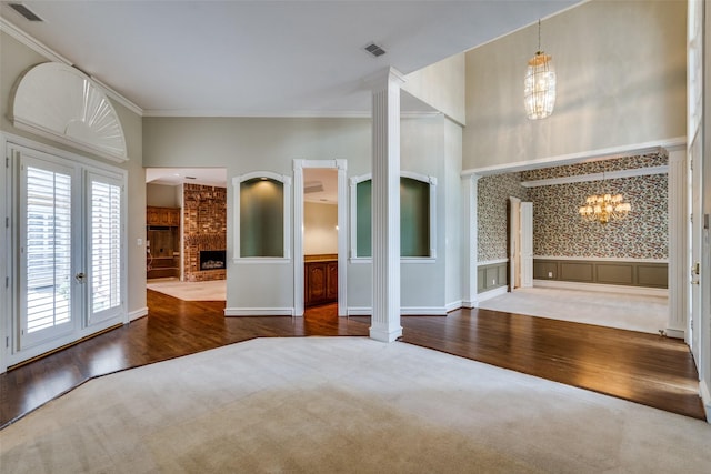 1405 Chesapeake Dr, Plano, TX 75093 - unfurnished bedroom with a chandelier, wood finished floors, a fireplace, ornamental molding, and decorative columns