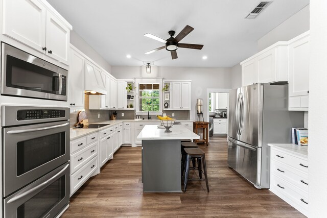 half bathroom featuring a sink, toilet, wooden walls, baseboards, and wood finished floors
