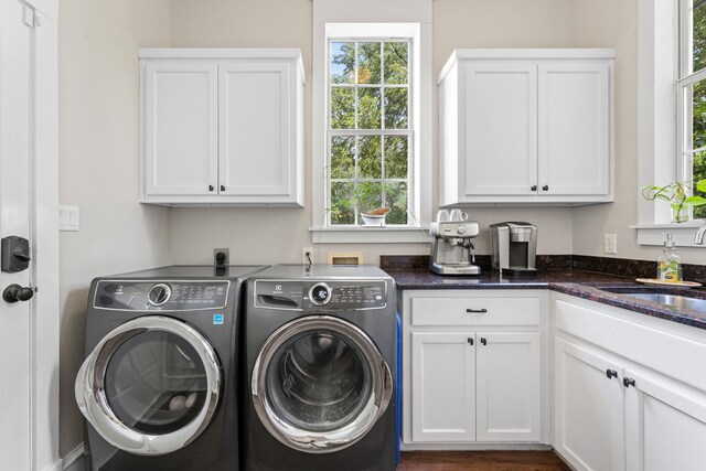 laundry area with a wealth of natural light, cabinet space, washing machine and clothes dryer, and a sink