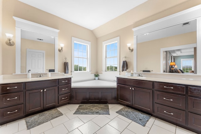 bathroom featuring a wealth of natural light, two vanities, and a sink