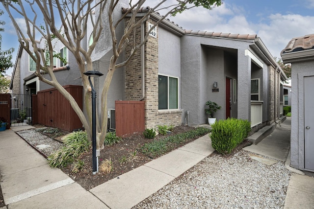 view of front of home featuring a gate, a tile roof, fence, and stucco siding