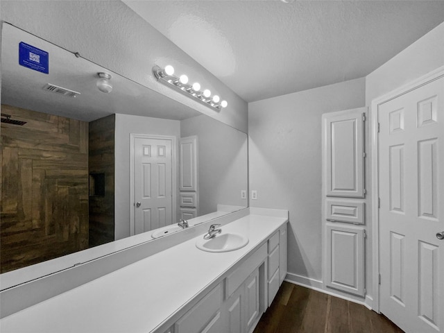 316 W 3rd Ter, Springtown, TX 76082 - full bathroom with a textured ceiling, baseboards, visible vents, wood finished floors, and vanity