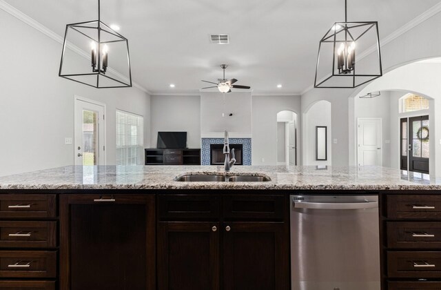 kitchen with arched walkways, stainless steel dishwasher, a healthy amount of sunlight, and a sink