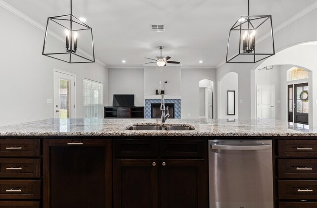 kitchen with arched walkways, stainless steel dishwasher, a healthy amount of sunlight, and a sink