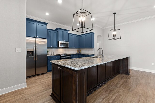 kitchen with blue cabinetry, light stone counters, tasteful backsplash, appliances with stainless steel finishes, and a notable chandelier