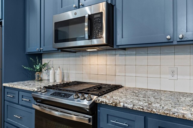 kitchen featuring backsplash, blue cabinets, light stone counters, and stainless steel appliances