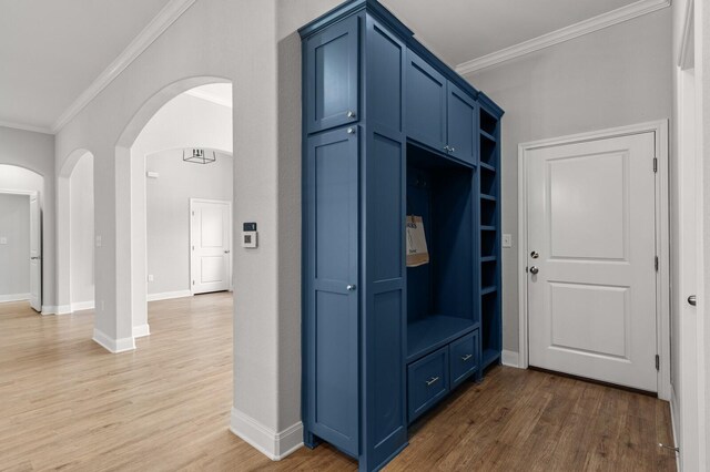 mudroom featuring baseboards, wood finished floors, arched walkways, and ornamental molding
