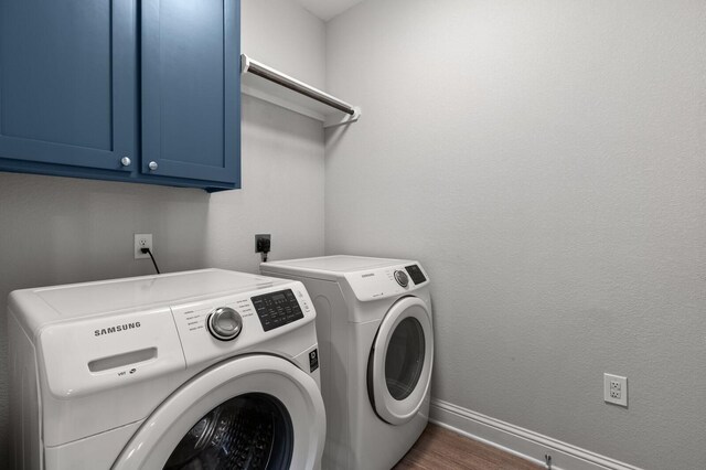 washroom with washing machine and clothes dryer, cabinet space, dark wood-type flooring, and baseboards