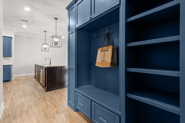 mudroom with crown molding, a sink, light wood-style floors, baseboards, and visible vents