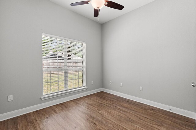 empty room with dark wood finished floors, baseboards, and a ceiling fan