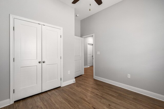 unfurnished bedroom featuring baseboards, a closet, a ceiling fan, and dark wood-style floors
