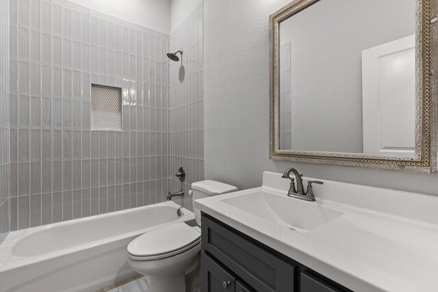 bathroom with a textured wall, vanity, shower / tub combination, and toilet