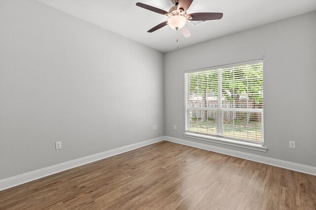 empty room featuring baseboards, wood finished floors, and ceiling fan