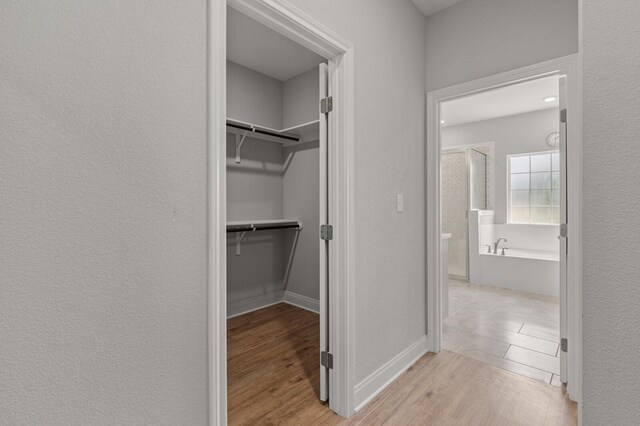 corridor with a textured wall and light wood-style flooring