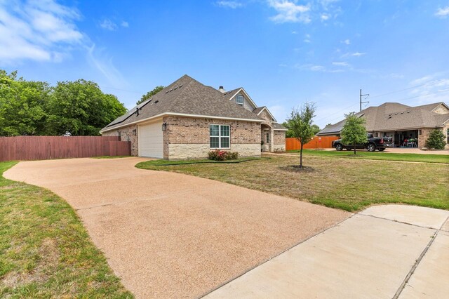 view of side of home with brick siding, a lawn, concrete driveway, and fence