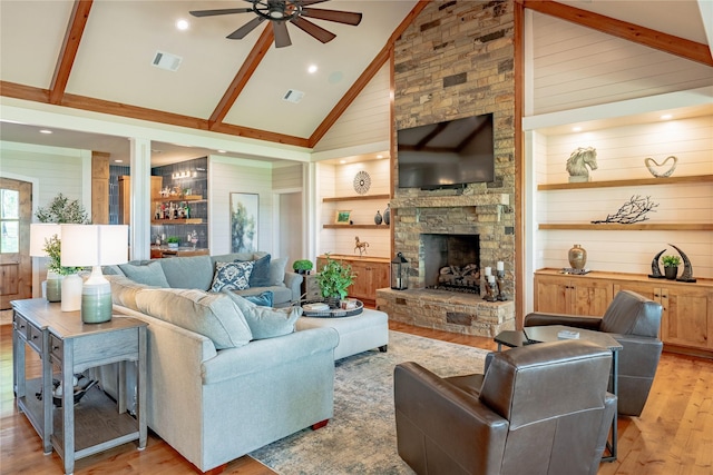 living room featuring high vaulted ceiling, a ceiling fan, light wood finished floors, wood walls, and visible vents