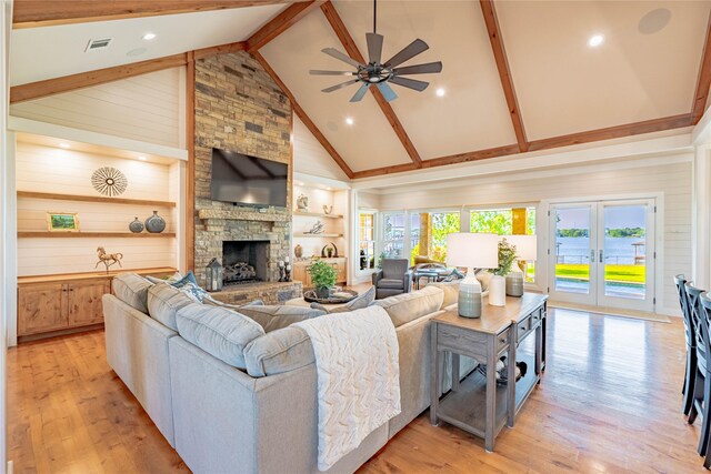living area featuring high vaulted ceiling, a stone fireplace, light wood-style floors, ceiling fan, and visible vents