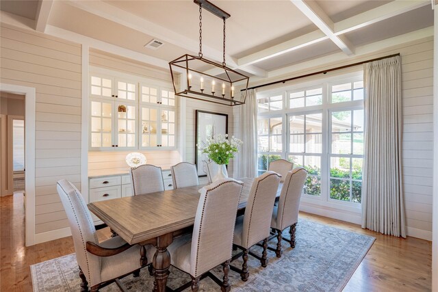 dining area featuring visible vents, wood walls, and a healthy amount of sunlight