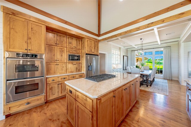 kitchen featuring light wood-type flooring, stainless steel appliances, decorative light fixtures, beam ceiling, and a kitchen island