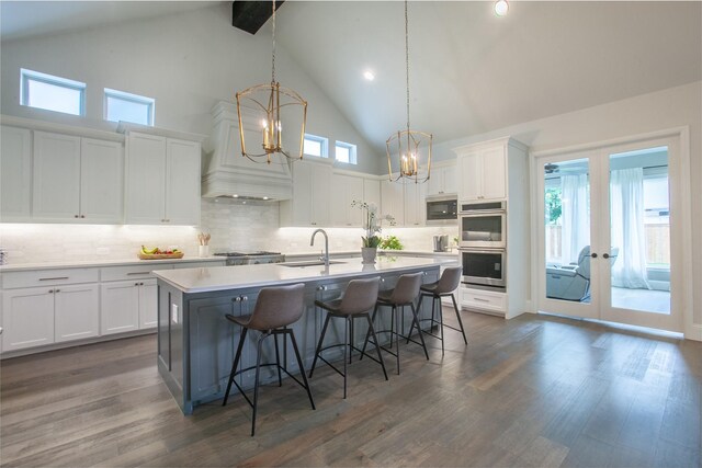 kitchen featuring appliances with stainless steel finishes, a sink, a breakfast bar area, high vaulted ceiling, and white cabinetry