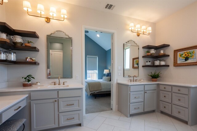 ensuite bathroom with tile patterned floors, vaulted ceiling, visible vents, and vanity