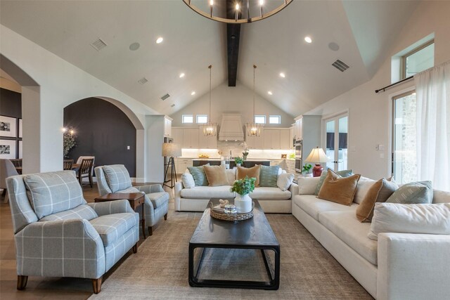 living area with an inviting chandelier, arched walkways, high vaulted ceiling, beamed ceiling, and visible vents