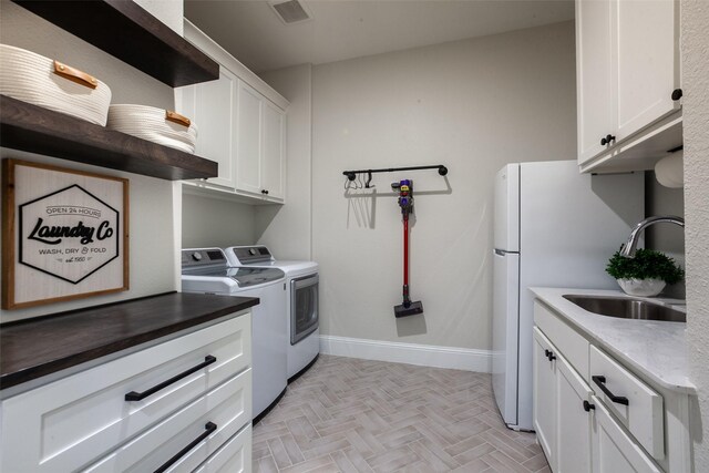laundry room featuring visible vents, baseboards, separate washer and dryer, a sink, and cabinet space